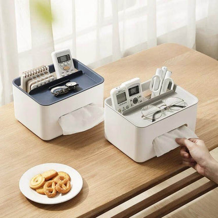 Two-Compartment Tissue Box And Remote Organizer For Desk on wooden table holding remotes, glasses and phone with pull-out tissues