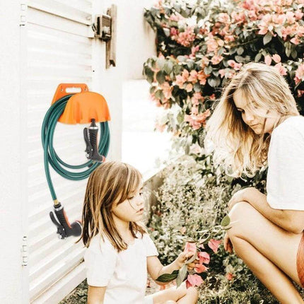Wall Mounted Plastic Water Pipe Holder For Garden Irrigation mounted on shed wall holding green hose with mother and child gardening nearby