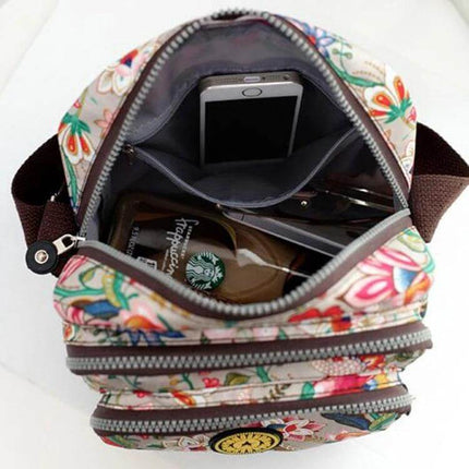 Women's Waterproof Nylon Shoulder Bag For Everyday Use with floral print, interior zipper pocket holding phone and sunglasses, compact organizer