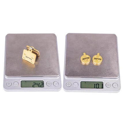 ZTTO Mountain Bike Brake Pads Full Metal Copper Base shown on scales, lightweight gold copper-base brake pads for mountain and urban trails