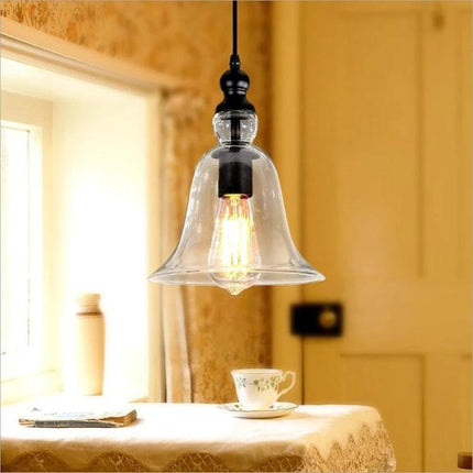 Glass Pendant Light for Kitchen and Dining Rooms at Home with clear bell-shaped glass shade over cozy dining table