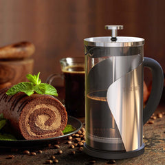 TBGENIUS 600ml French Press Coffee Maker with 4-Level Filtration next to a dessert roll and coffee beans