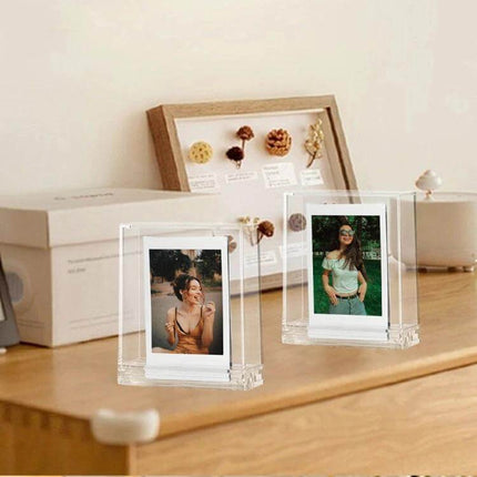 Photo Frame Stand for Polaroids - Double-Sided for Easy Display showing two clear polycarbonate holders with Polaroid photos on a wooden shelf
