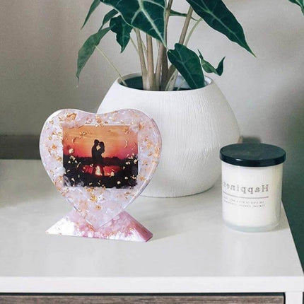 Heart Shaped Silicone Photo Frame Mould For Craft Projects showing resin heart frame with photo, gold flakes, on shelf with plant and candle