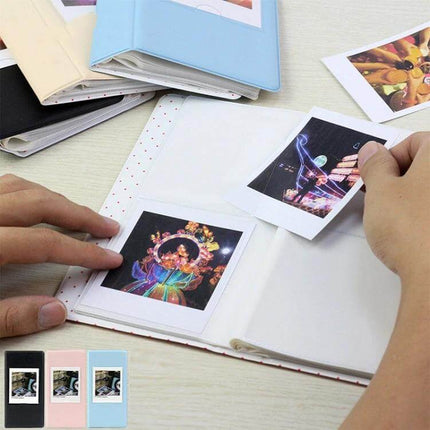 Instax Photo Album 64-Piece Capacity For Keepsakes showing hands inserting 8.8×10.9 cm prints into snag-free insert pages