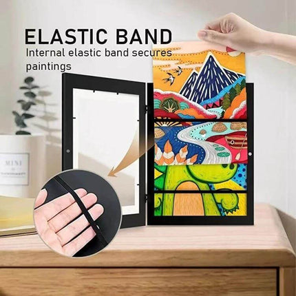 Kids Magnetic Front-Opening Art Frame For Photos And Drawings showing hand placing colorful kids artwork into a black magnetic front-opening frame with elastic band storage