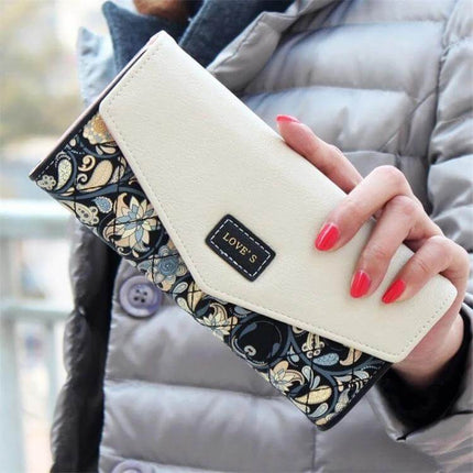 Ladies Floral PU Leather Clutch Wallet For Everyday Use – cream and navy floral PU leather clutch wallet with hasp closure held by hand (19×9.5×2.5 cm)