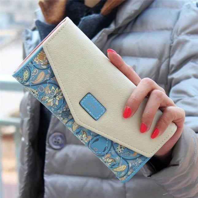 Ladies Floral PU Leather Clutch Wallet For Everyday Use in cream and blue floral pattern held by hand with red nails