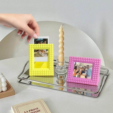 Mini 3 Inch Rivet Vertical Color Photo Frame For Polaroid Photos displayed in yellow and pink on a mirrored tray holding Polaroid-style prints