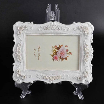 Plastic Transparent Photo Frame Holder Set Of 10 Assorted Sizes displaying an ornate white decorative photo frame on a clear plastic stand