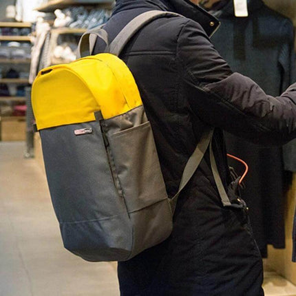 POFOKO XY Series 14-15.4 Inch Laptop Backpack for Everyday Use in yellow and grey on a commuter wearing a black coat, showing side pocket and padded straps