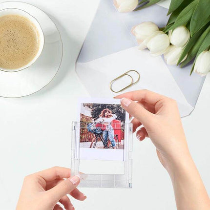 Polaroid Square Photo Frame Magnetic Building Blocks Fridge Magnet showing hands inserting a Polaroid square photo into a clear magnetic frame on a white desk
