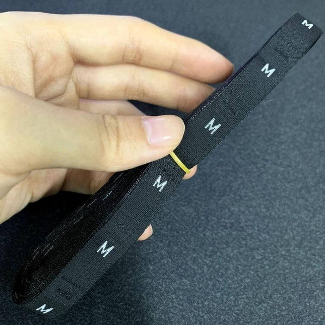 Polyester Clothing Size Labels 3.4 x 1.2 cm Roll 380 pcs - black polyester size label roll with repeated 'M' markings held by hand