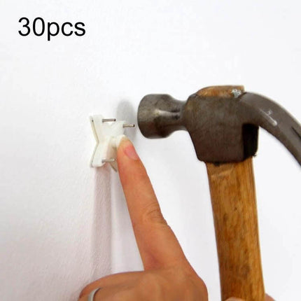 Press-Free Hanging Nail Hooks 30Pcs Set For Photo Frames - finger pressing ABS hook being hammered into wall to hang frame
