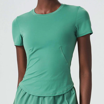 Small Waist Yoga Top With Short Sleeves In Black For Studio Practice modeled in green short-sleeve training shirt with fitted small-waist cut