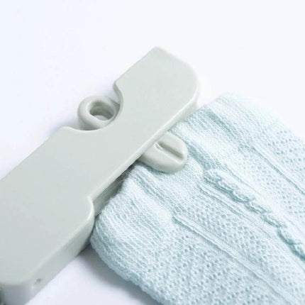 Travel Foldable Clothes Hanger On The Go Anti Skid compact ABS clip hanger holding a light knit sock for travel drying and space-saving packing