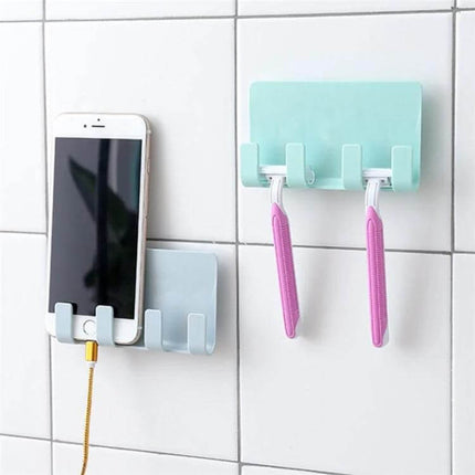 Wall-Mounted Phone Charging Stand With Strong Adhesive holding smartphone and charging cable mounted on tiled wall, plus adjacent hook holding razors
