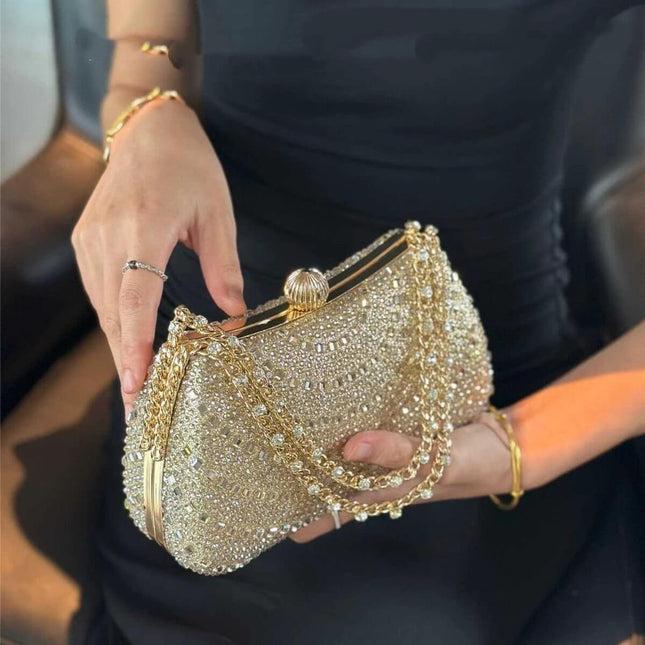 Wine Red Pillow Clutch Bag With Inlaid Diamonds And Chain Strap held by woman in black dress, quilted pillow shape with gold-tone chain and diamond accents