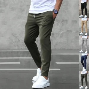Man wearing olive green joggers with a white t-shirt and white sneakers.