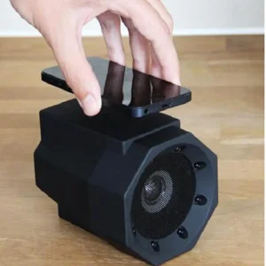 Black portable speaker with a smartphone placed on top, designed for wireless audio playback.