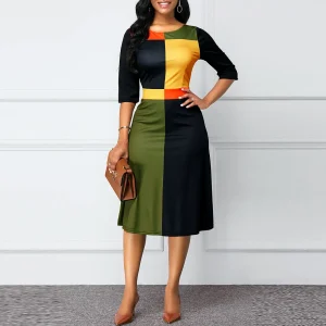 A woman wearing a color block midi dress with sections of black, yellow, orange, and green.