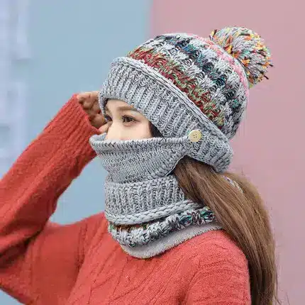 Cozy Korean Winter Knitted Hat for Ultimate Warmth and Style 7 A Woman Wearing A Knitted Hat With A Pom-Pom And A Matching Scarf, Both In Gray And Colorful Patterns.