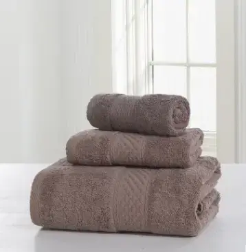 Luxurious Thick Cotton Bath Towel & Robe Set for Spa-Like Comfort 9 Three Stacked Brown Towels Of Varying Sizes On A Flat Surface.