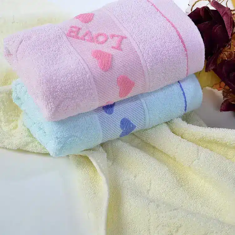 Caring Pure Cotton Face Towel for Gentle Daily Use 7 Two Soft Towels Stacked Together, One Pink With Hearts And One Light Blue With Hearts.