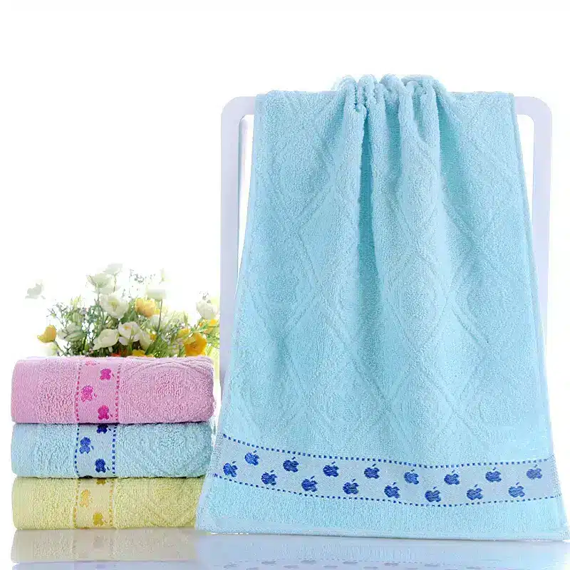 Ultra-Soft Cotton Face Towel for Daily Comfort and Care 9 Light Blue Decorative Towel Hanging With Patterned Border And Three Stacked Towels In Pink, Yellow, And Green.