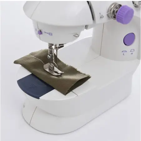 Compact Multifunctional Mini Sewing Machine for Home Projects 6 A Compact Sewing Machine Stitching A Piece Of Green Fabric On A White Surface.