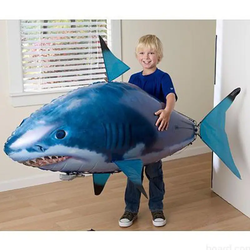 Remote Control Shark Toy - Swim and Fly, Fun for All Ages 6 A Child Holding A Large Inflatable Shark Toy In A Room With Natural Light.