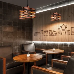 Two wooden pendant light fixtures hanging above wooden tables in a café setting.