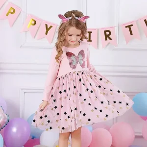 A young girl wearing a pink dress with a butterfly design and star patterns, standing in front of balloons.