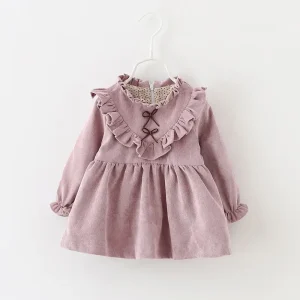 A pink corduroy dress featuring ruffles and a bow detail at the front, designed for children.