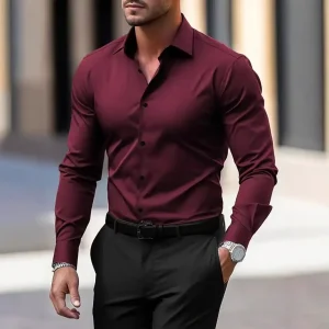 Man wearing a fitted burgundy dress shirt with black pants and a watch.