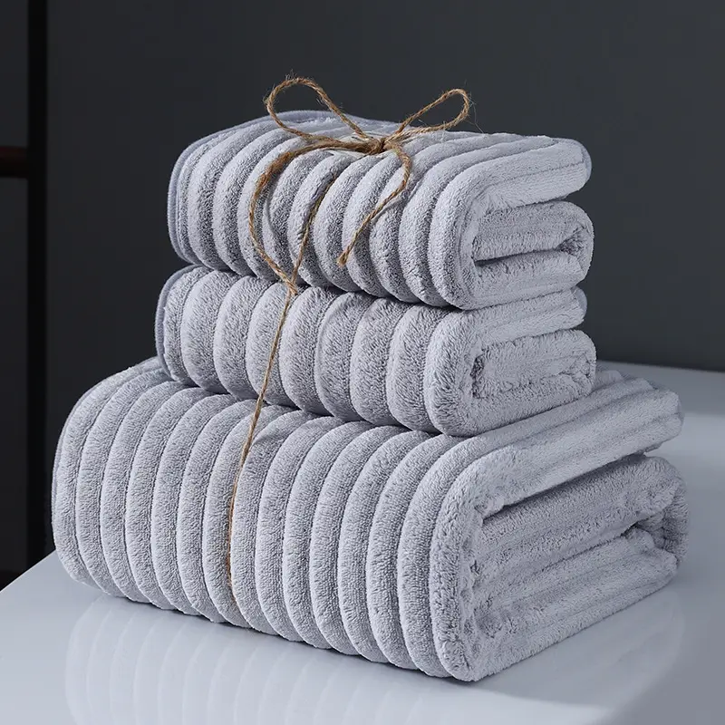 Ultra-Soft Coral Fleece Towels for Quick Absorption & Comfort 6 Three Neatly Stacked Gray Towels Tied Together With Twine On A Flat Surface.