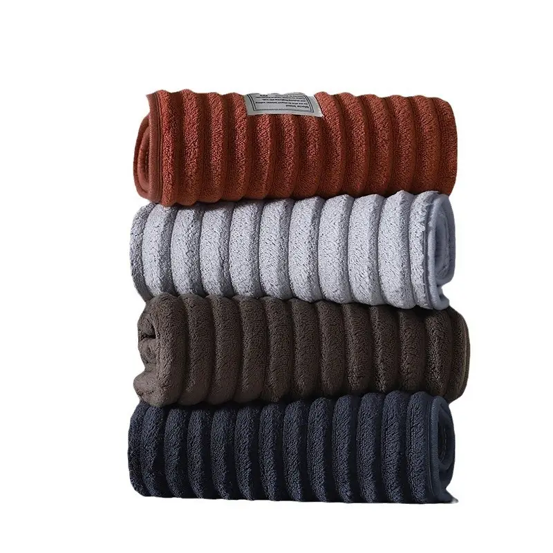 Ultra-Soft Coral Fleece Towels for Quick Absorption & Comfort 3 Four Rolled Towels In Orange, White, Brown, And Navy Blue Arranged In A Stack.