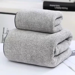 Three gray towels stacked neatly on a surface with a soft texture.