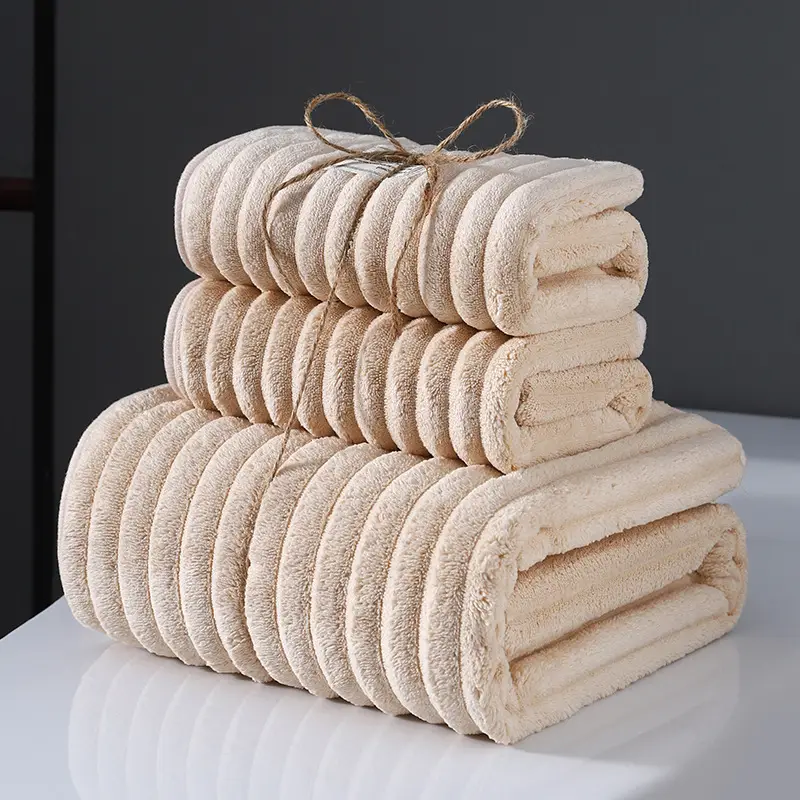 Ultra-Soft Coral Fleece Towels for Quick Absorption & Comfort 2 Three Neatly Folded Beige Bath Towels Stacked With A Twine Bow On Top.