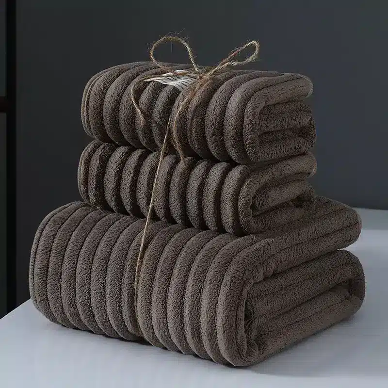 Ultra-Soft Coral Fleece Towels for Quick Absorption & Comfort 5 Three Neatly Stacked Brown Towels Tied Together With Twine On A Flat Surface.