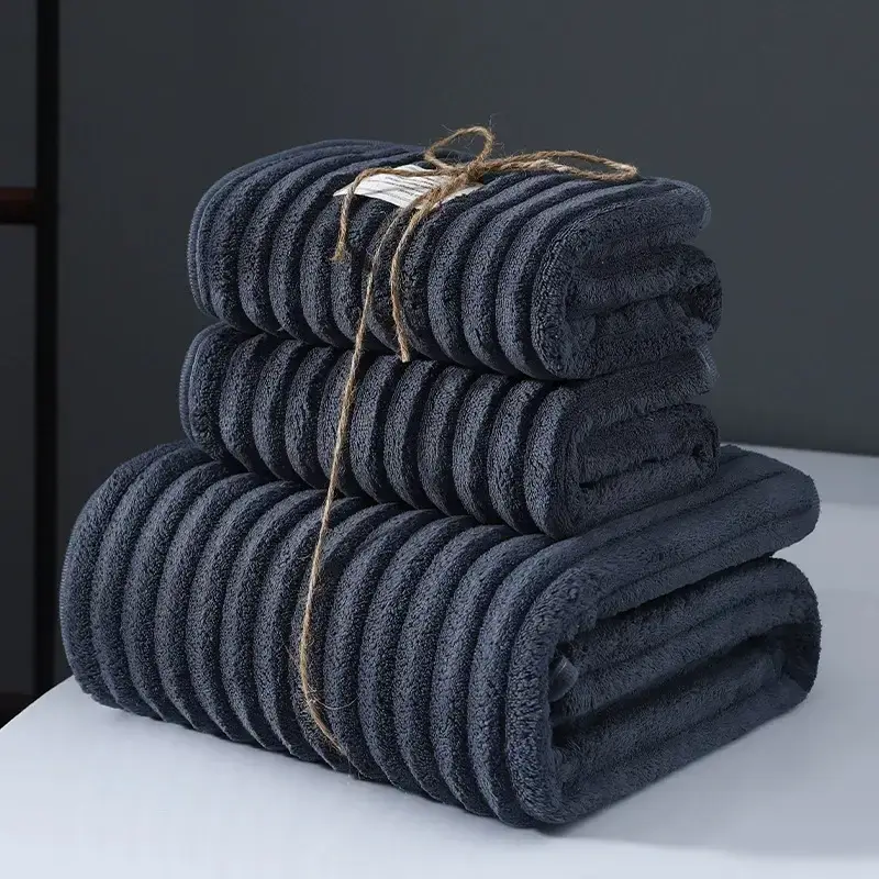 Ultra-Soft Coral Fleece Towels for Quick Absorption & Comfort 4 Three Neatly Stacked Dark Gray Towels Tied With Twine On A Flat Surface.