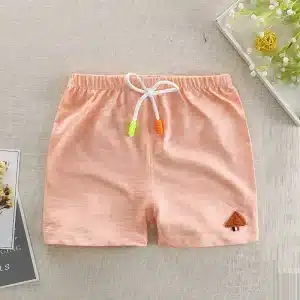 Light peach-colored shorts with an elastic waistband and contrasting drawstring, featuring a small logo patch.