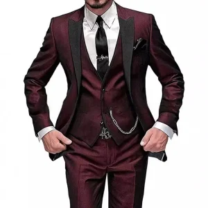 Man wearing a burgundy suit with a black tie and chain detail on the vest.