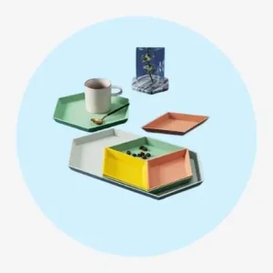 Set Of Assorted Colored Trays In Various Shapes With A Cup And A Small Bowl.