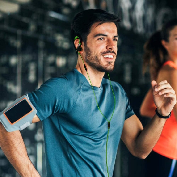 Mucro MB-232 Sport Earbuds: Perfect for Running and Gym Workouts 7 Man Running While Wearing Earphones And An Armband For A Smartphone In A Gym Setting.