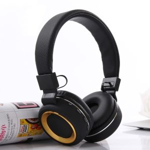 Black wireless headphones with gold accents and control buttons on the side, placed next to a magazine.