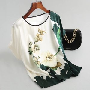 Short sleeve top featuring a floral design in green and beige on a white background.