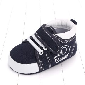 Black and white baby sneaker with Velcro strap, suitable for infant wear, featuring comfortable fabric and stylish design. Perfect for toddler footwear needs on Syndmart.