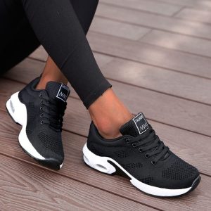 Comfy black athletic sneakers on wooden floor, casual sports footwear, breathable mesh design, stylish running shoes for women, Syndmart fitness shoe collection.