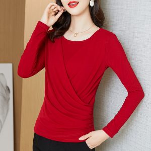 Woman wearing a red long sleeve top with a draped design and a round neckline.